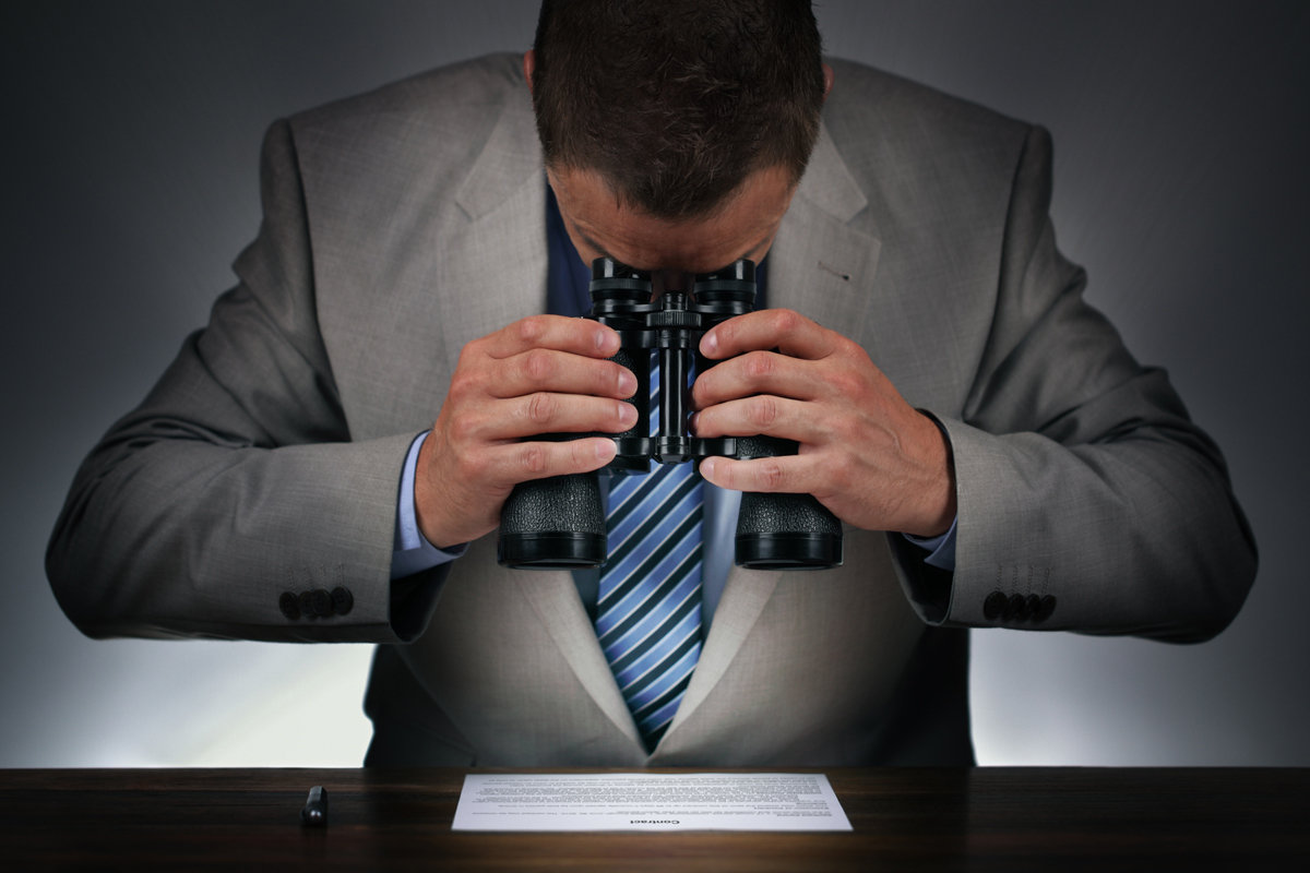 man with binoculars reading the fine print contract examine 100745619 large